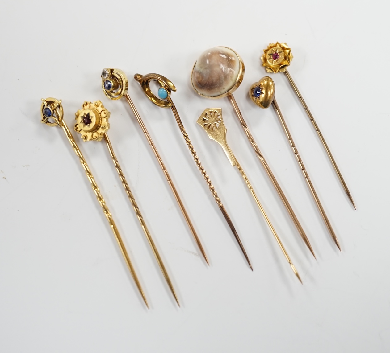 Eight assorted early 20th century and later yellow metal and gem set stick pins, including six 15ct, one 585 and one unmarked yellow metal, largest set with sapphire, 59mm, gross weight 11 grams.